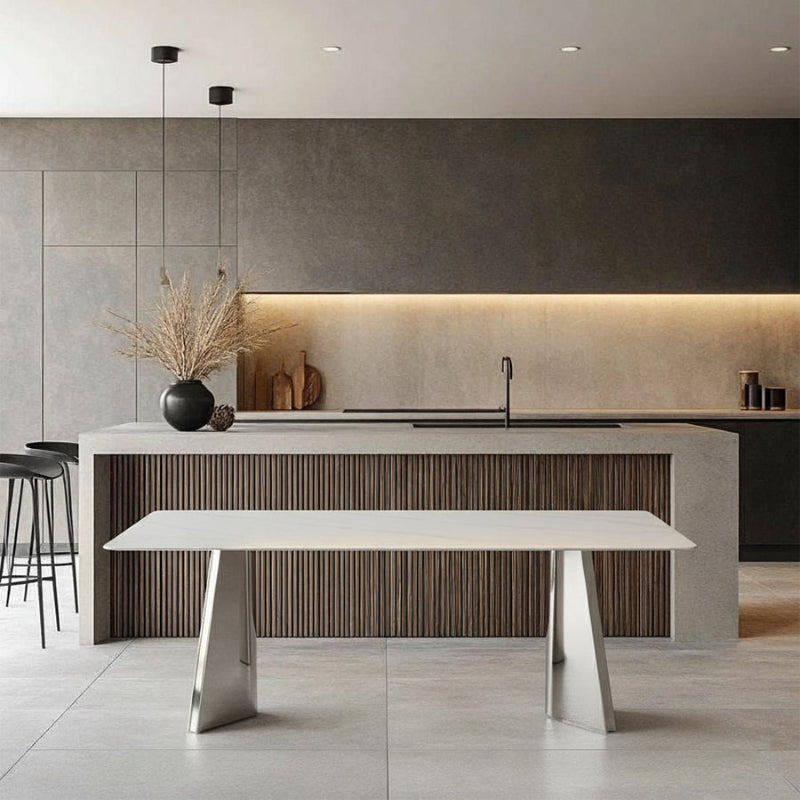 ARYLLIS sintered stone dining table placed beside a contemporary kitchen bar area, highlighting its marble-pattern top and mirror-finish steel base.