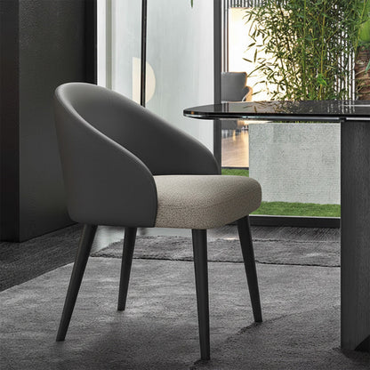 NOTI Chair positioned next to a dining table on a gray carpet, black metal legs, dark gray leather backrest, light gray fabric seat.