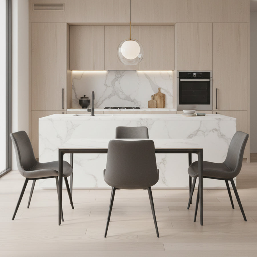 RAG Contemporary Sintered Stone Dining Table with a white marble-look top and a dark gray aluminum frame. The table is centered in a modern kitchen/dining space with light wood cabinets and a large marble island.