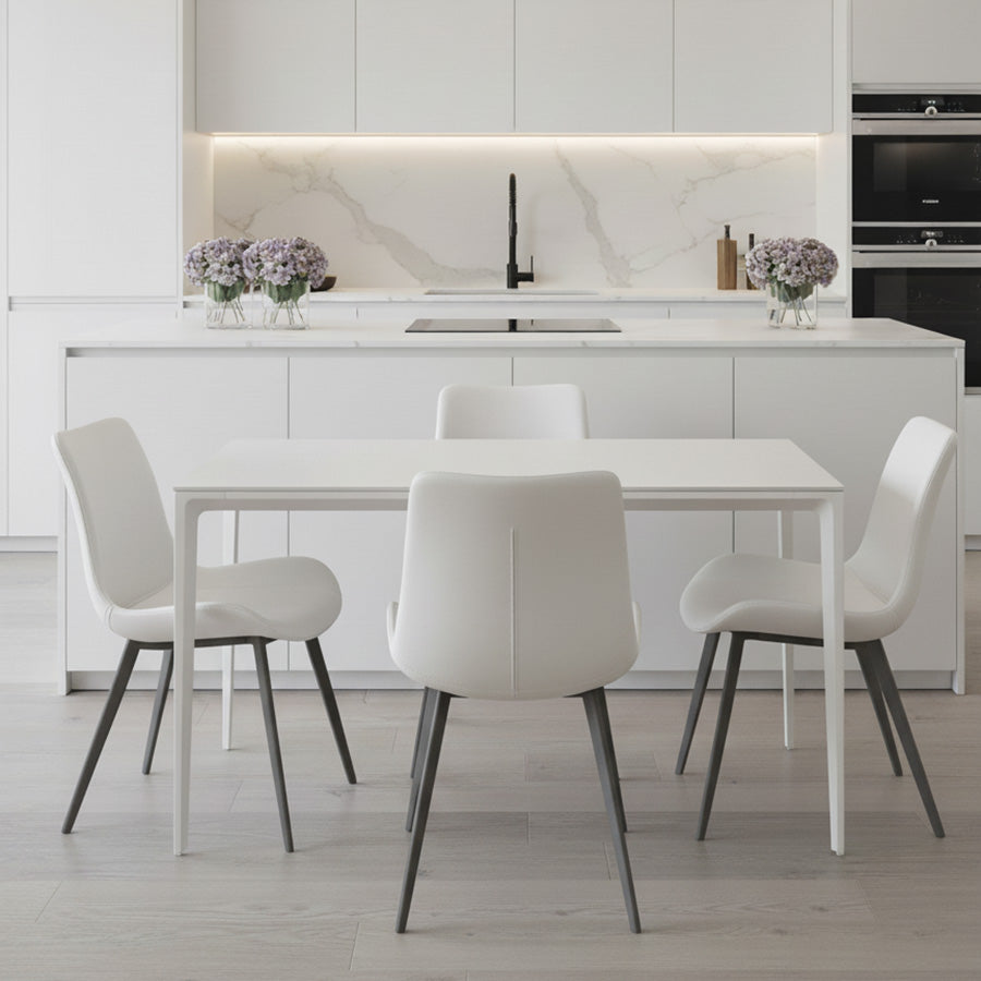 RAG Contemporary Dining Table with a white top and white aluminum base, set in a bright, all-white modern kitchen and dining area. The table is surrounded by four white dining chairs with dark legs.