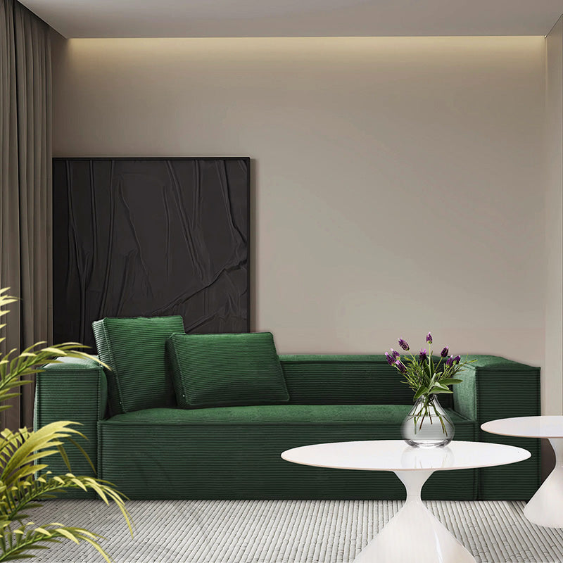 Modern living room featuring CUBE green corduroy sofa with deep seating, minimalist coffee tables, and contemporary wall art.