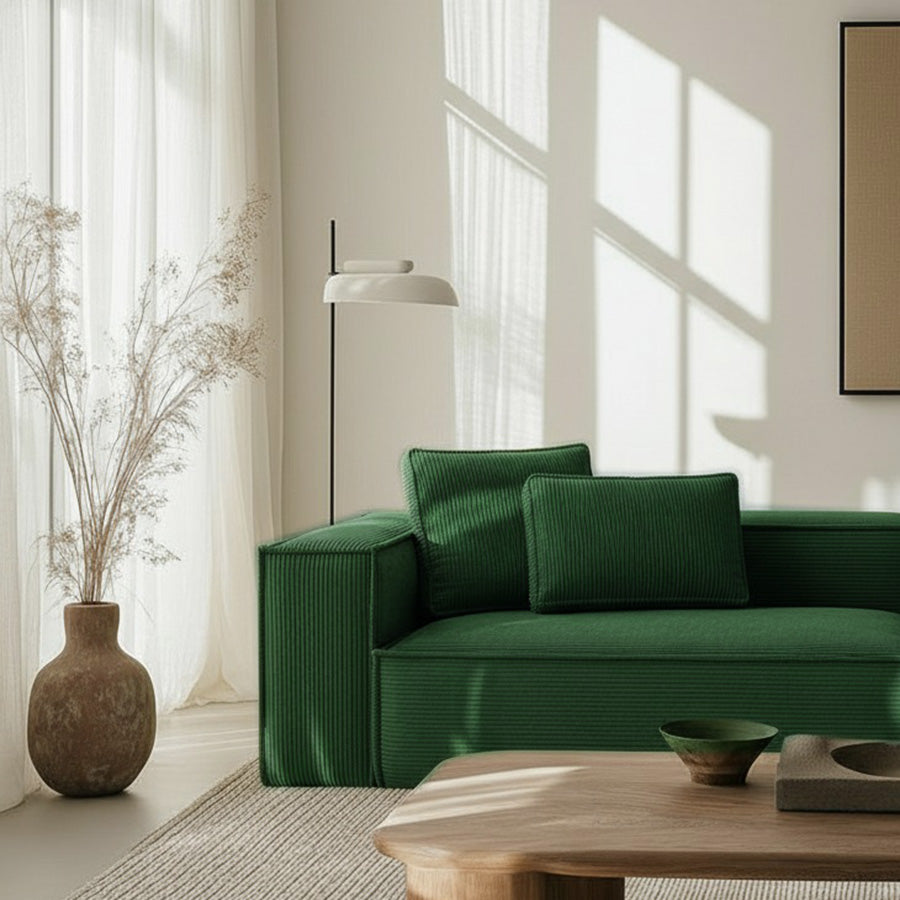 Close-up of CUBE frameless sofa in forest green fabric in a bright, sunlit room with minimalist decor and natural textures.