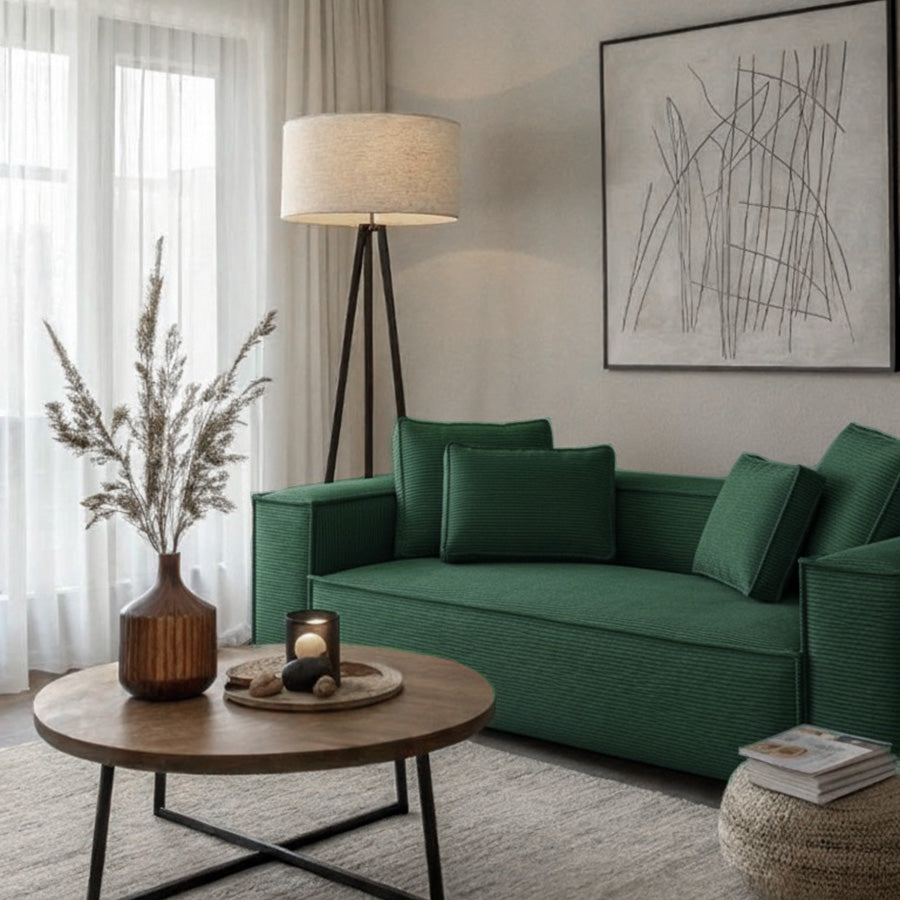 CUBE modular green sofa in a cozy home setting with a tripod floor lamp, wooden coffee table, and soft neutral interiors.