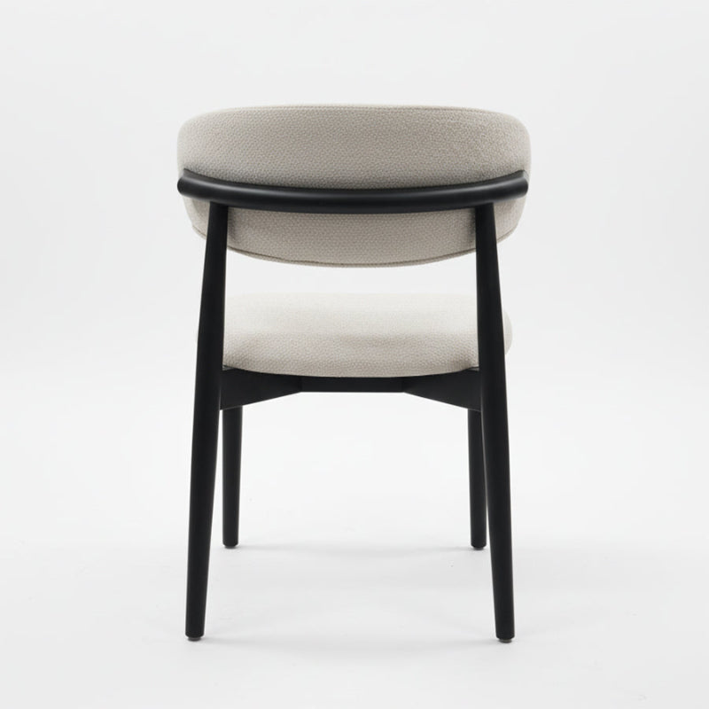 Back view of the CROIST chair, highlighting the unique curved black wood backrest and supportive off-white fabric cushion.
