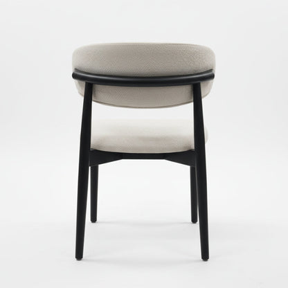 Back view of the CROIST chair, highlighting the unique curved black wood backrest and supportive off-white fabric cushion.