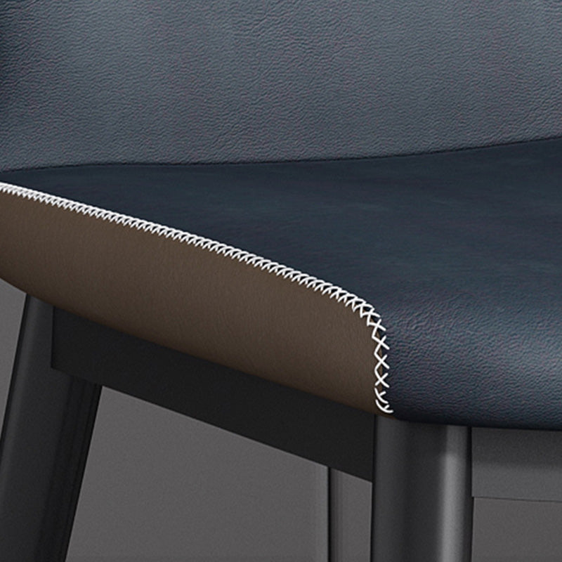 Detailed view of the BF chair's dark blue faux leather seat edge, showing the brown backing and the close-up texture of the white contrast stitching near the metal frame.