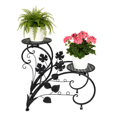 FLORON Black Wrought Iron Two-Tier Flower Stand, featuring intricate vine, leaf, and scrollwork design. Includes two circular mesh planter platforms with flowerpots, front view on a white background.