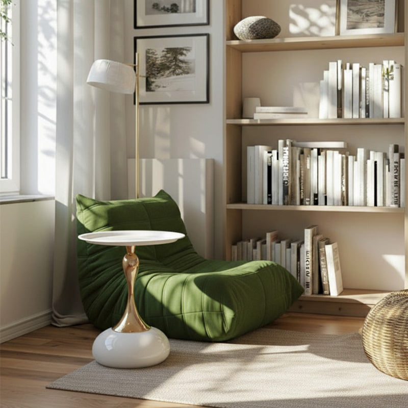White and gold Golp side table placed in front of a green Togo sofa in a cozy living room setting