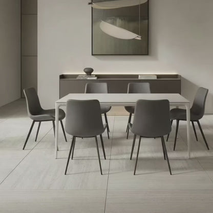 Contemporary Dining Table with a white top and white aluminum base, set in a bright, all-white modern dining area. The table is surrounded by six grey dining chairs with dark legs.