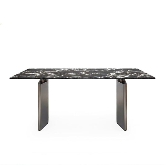 Front perspective view of the 180cm /71in DIMON dining table, featuring a dramatic black Sintered Stone top with white veining, set on two matte gunmetal steel angular bases against a pure white background.