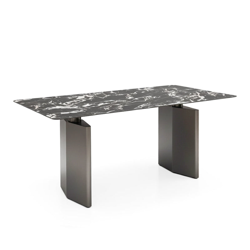 Angled oblique view of the DIMON dining table on a white background, showcasing the rich black Sintered Stone surface and the bold, architectural lines of the two grey gunmetal steel pedestal legs.
