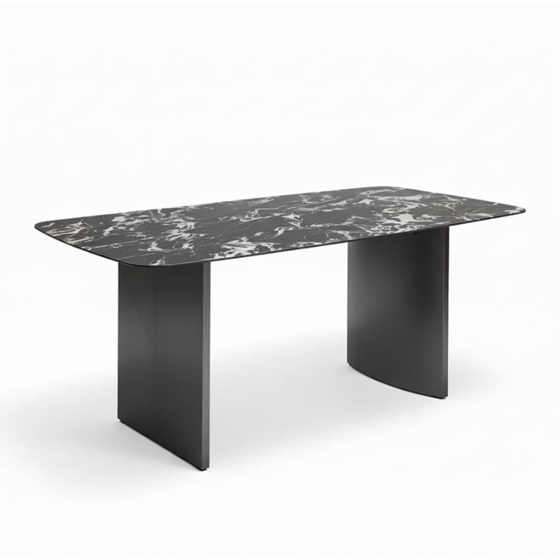 Angled perspective of the OLIV dining table showing its rounded edges, sintered stone surface, and modern stainless steel base.