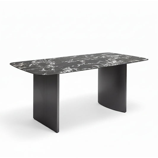 Angled perspective of the OLIV dining table showing its rounded edges, sintered stone surface, and modern stainless steel base.