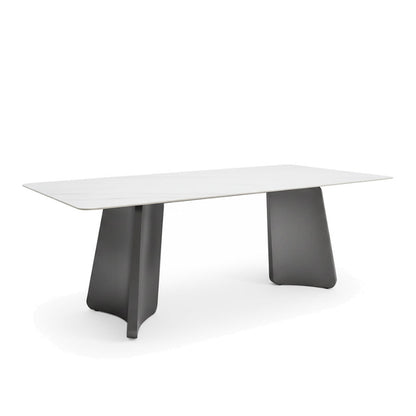 Left-angled oblique view of the PETLS dining table on a white background, showcasing the sleek Sintered Stone top and the bold, geometric lines of the dark steel legs from a higher perspective.