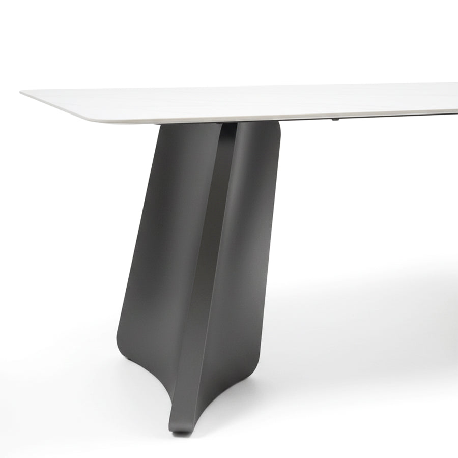 Close-up detail shot of the PETLS dining table's wide, angled gunmetal grey steel pedestal leg, highlighting its smooth finish and sturdy construction.