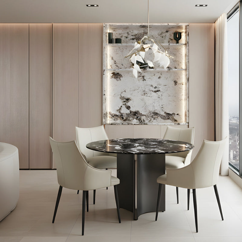 LUMARA 90cm (35.5in) round dining table with a bulgary black marble sintered stone top styled in a contemporary dining room with warm lighting.