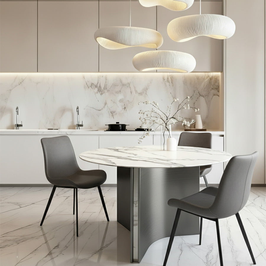 Lumara 47-inch round sintered stone dining table with white marble top and gray stainless steel legs, styled with SADE upholstered dining chairs