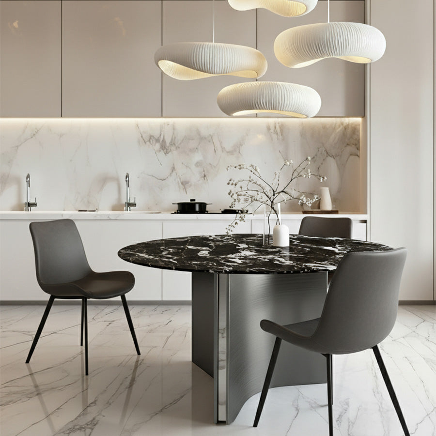 Lumara 47-inch round sintered stone dining table with black marble top and gray stainless steel legs, styled with SADE upholstered dining chairs