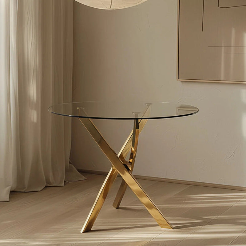TRINITY round glass dining table styled in a modern room, showcasing its clear 39-inch glass top and contemporary gold mirror-finish stainless steel base.