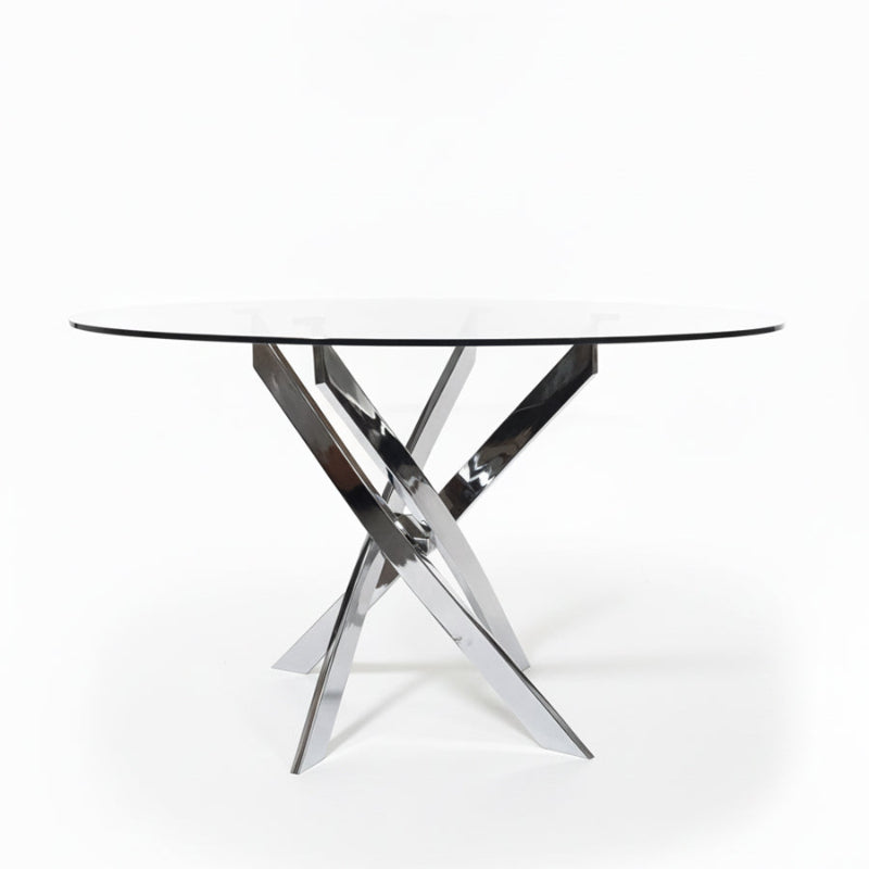 45-degree angled view of the VERDIS round glass dining table featuring a clear tempered glass top and mirror-finish stainless-steel legs