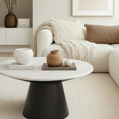 Bentrio 32-inch round coffee table with matte black stainless steel base, placed in front of a white sofa in a modern living room setting