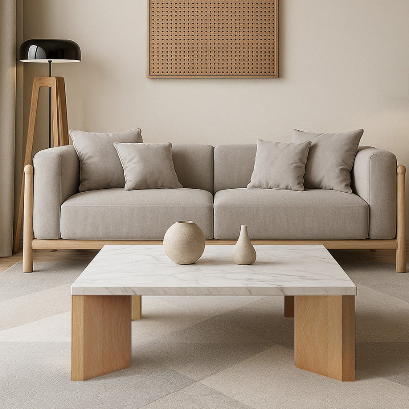 Syley square coffee table with snow mountain white top and natural oak base, placed in front of a sofa in a warm, natural wood-toned living room